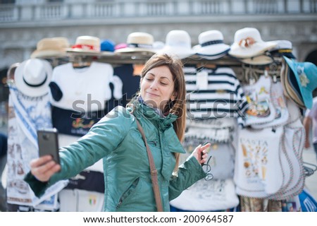 A beautiful young woman taking a selfie with mobile phone in Venice.