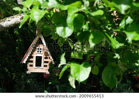 birdhouse on tree branch in summer garden.