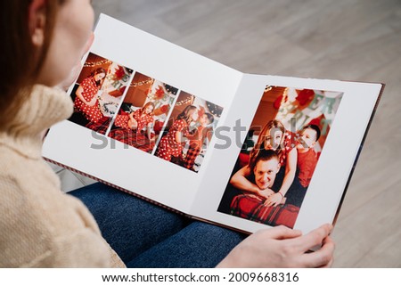 top view. a woman flips through the pages of a photobook from a new year's family photo shoot. printed products. Store photos in an album. services of photographer and designer.