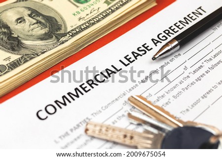 Commercial lease agreement form close-up. House keys, pen and money on office desk. Close-up photo