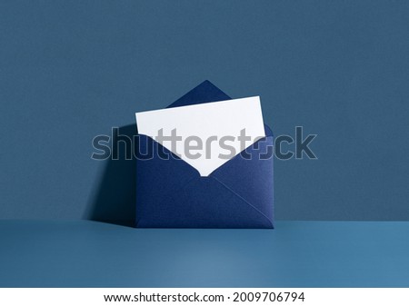 White card in a dark blue seal leaning against a blue wall. Invitation mockup, long shadow. Royalty-Free Stock Photo #2009706794