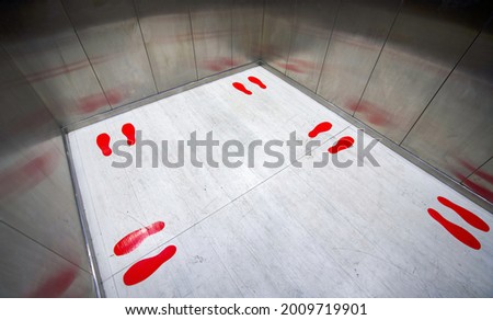 Red footprint symbol inside the elevator show standing position and distance of each person. Social distancing to reduce the spread of infectious diseases Covid-19. New normal concept.