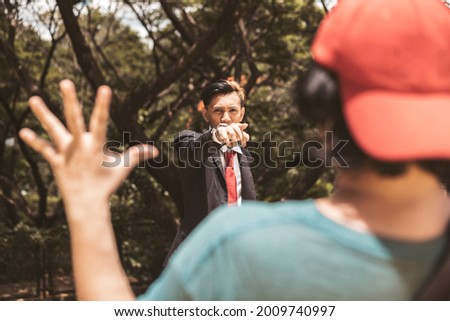 An angry young university student accuses another man of wrongdoing or a crime. Pointing his hand aggressively. The accused man holds his hands up but in denial. Royalty-Free Stock Photo #2009740997