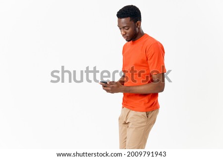 African American in a T-shirt with a mobile phone in his hand on a Light background 