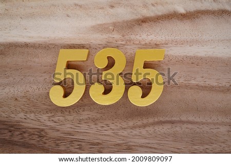Gold numerals 535 on a dark brown to off-white wood pattern background.