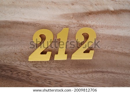 Gold numerals 212 on a dark brown to off-white wood pattern background.