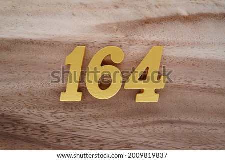 Gold number 164 on a dark brown to white wood grain background.