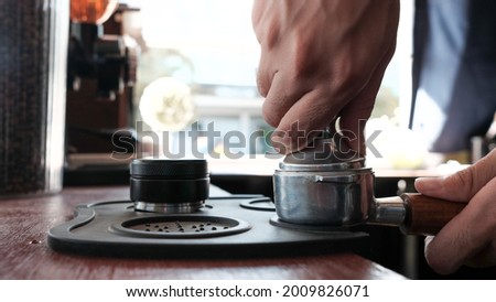 A hand tamping the portafilter on a coffee bar Royalty-Free Stock Photo #2009826071