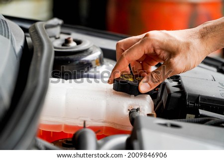 mechanic inspects the expansion tank with pink antifreeze. Vehicle coolant level in the car's radiator system. auto parts Royalty-Free Stock Photo #2009846906