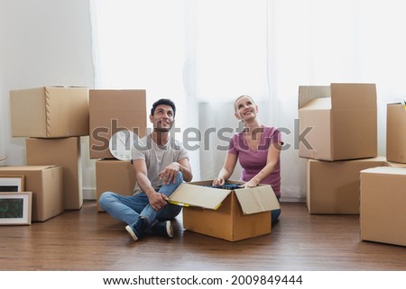 happy Caucasian couple sit on with stuff in boxes moving to new home. Adult men and women look at the top and dream to plan for the future of their families. Family and real estate concept