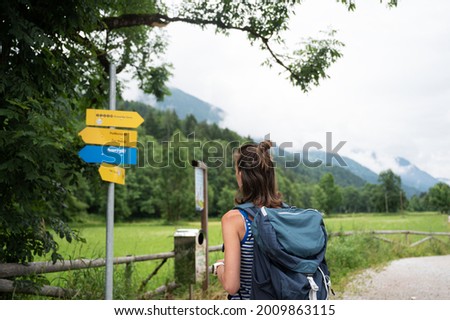 Young female hiker with a backpack looking at a signpost deciding which way to go.