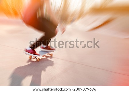 Unrecognizable skateboarder on his board. Photo was taken in backlight in golden hour. blur effect
