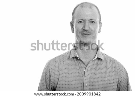 Studio shot of bald businessman with beard stubble isolated against white background in black and white