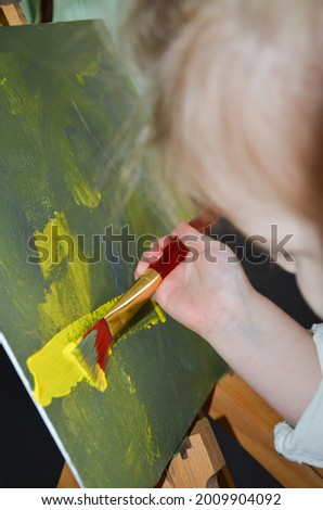 photo little girl artist, child draws a picture on canvas in the house