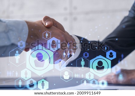 Recruitment concept to hiring of a new talented specialists for international company. Handshake to sign in of employment agreement. Social media hologram icons over the table with documents.