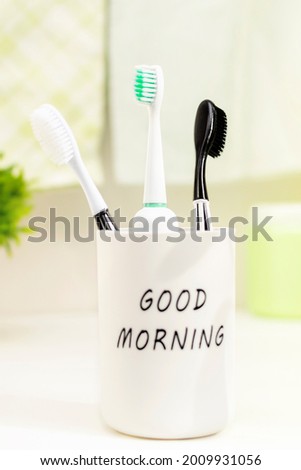 Close-up of toothbrushes in a glass on the countertop in the bathroom on a sunny morning. 