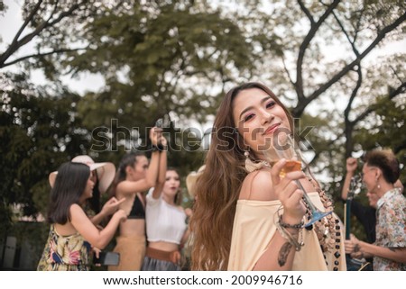 A young asian woman enjoys a boho themed party or festival outdoors with friends.