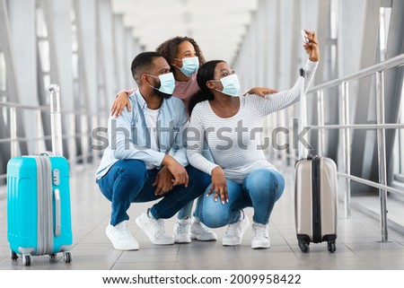 Runway Selfie Concept. African American Family Of Three Wearing Disposable Face Masks Taking Selfportait Picture With Smartphone In Airport Terminal, Travelling Together During Covid Epidemic