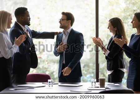 Grateful diverse team expressing recognition, appreciation, acknowledge to leader, clapping hands, touching shoulder, congratulating boss on achieve, good work result, applauding promoted coworker Royalty-Free Stock Photo #2009960063