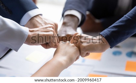 Diverse business team making group fist bump. Employees engaged in teamwork, keeping community spirit, expressing solidarity, trust, unity, friendship. Close up of multiethnic hands Royalty-Free Stock Photo #2009960417