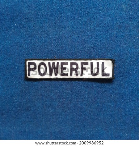 Powerful words embroidered on white cloth on blue background. 
