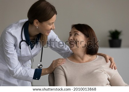 Happy positive medical professional, doctor, nurse giving support and help to senior female patient at appointment, touching shoulders. Old woman visiting, consulting young physician in office Royalty-Free Stock Photo #2010013868