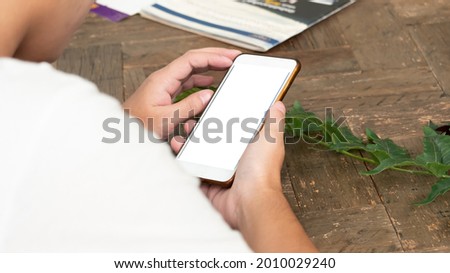 Mockup image blank white screen smart phone.men hand holding texting using mobile relax on sofa at home