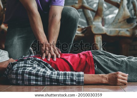 young man is helping his unconscious friend and stop breathing on the floor with CPR. Because the young man had trained to help patients with sudden cardiac arrest or CPR Cardiopulmonary Resuscitation Royalty-Free Stock Photo #2010030359