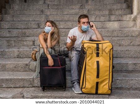 Sad tourist couple with mask and luggage ready for summer vacations trip worried about coronavirus test results and immunity passport. Vacations cancellations due to post covid travel restrictions.