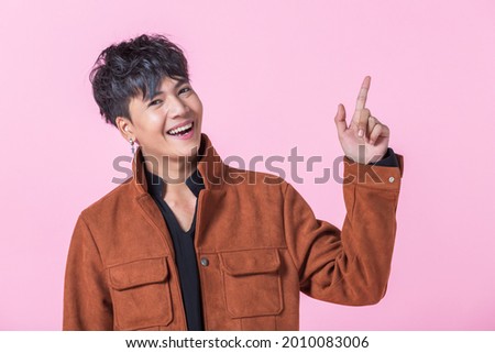 Asian a man handsome young pointing with two hands and fingers to the side eyes looking at camera in love isolated on pink blank copy space studio background.