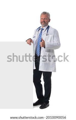 Portrait of mature doctor with thumb up holding blank placard isolated on white background