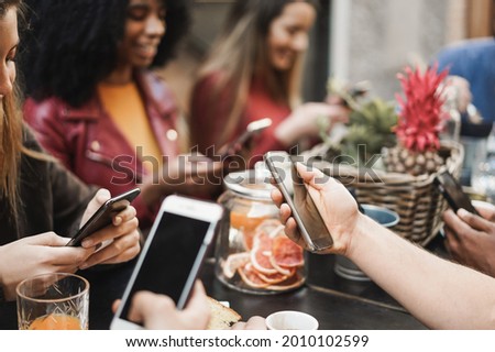 Multiracial friends using mobile phones outdoor at vintage bar restaurant - Focus on right hand holding smartphone Royalty-Free Stock Photo #2010102599