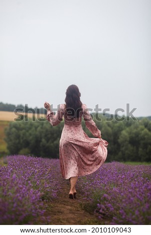 fantasy woman bride elegant long vintage white dress gown. hairstyle dark hair, walks bloom lavender field  purple flowers grass. Happy escaped run princess. sunset sun light
