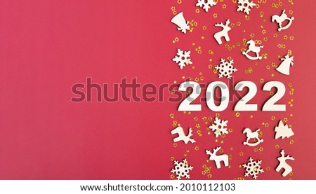 Wooden numbers for new year 2022 with stars and christmas decor on red background with copy space. Banner format