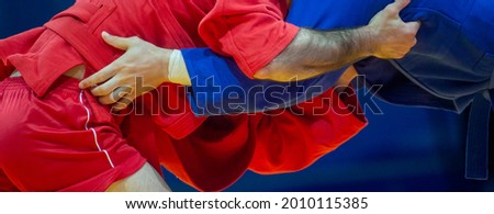 Two men in blue and red wrestling on a yellow wrestling carpet in the gym. Professional sport concept. Horizontal sport poster, greeting cards, headers, website