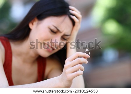 Sad asian woman complaining holding engagement ring in the street Royalty-Free Stock Photo #2010124538