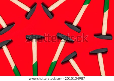 Pattern of hammers isolated on red background. Shop banner with construction tools. New Year or Christmas festive backdrop. One of the basic home use instrument for hammering nails. Building design.