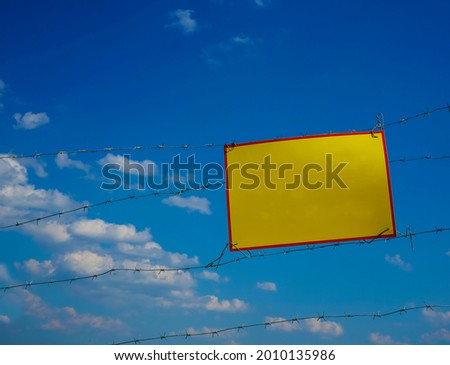 empty frame. restricted area.  no passage. Hazard warning sign. You cannot go beyond this border. Danger area.  blue sky and white clouds. Barbed wire.