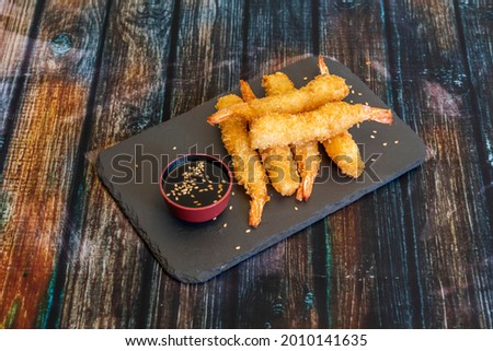 King prawns battered in panko raincoat with a bowl of soy sauce and sesame seeds on a black slate plate Royalty-Free Stock Photo #2010141635