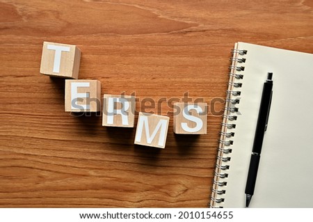 On a white damaged wood board, wooden word cubes are arranged in the letters TERMS.