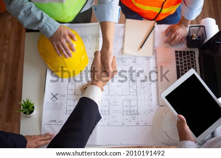 Hand in hand between project contractors and customers due to negotiation of expenses and investments, construction and repair of residential buildings. Royalty-Free Stock Photo #2010191492