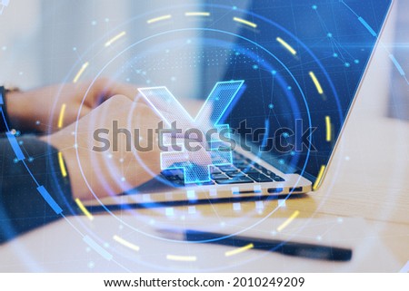 Close up of hands at desktop using laptop with glowing yen hologram. Currency and finance concept. Double exposure