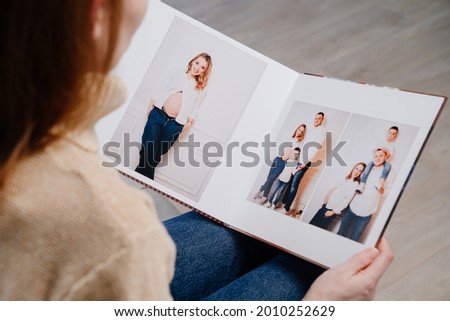 top view. woman watches photobook from photo shoot of family. storage of photos in photo album. work of designer, photographer and printer. memory of important moments of life Royalty-Free Stock Photo #2010252629