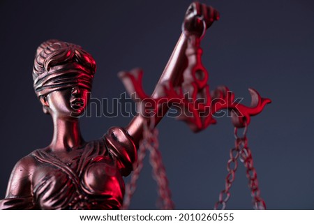 Statue of justice on grey background. Red contrast light. Place for text.