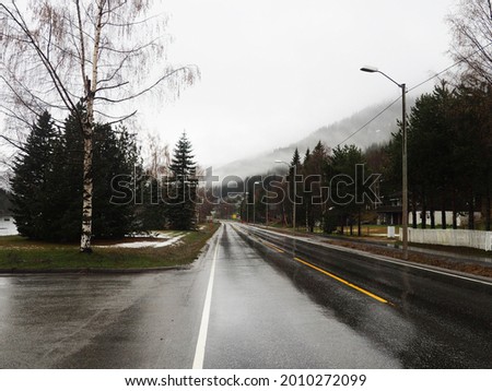 Gloomy landscape with fog on the Norwegian fjords, the road through the village.