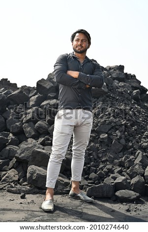 A young man stands next to coal mine