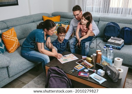 Mother explaining to her family the assembly point map while preparing emergency backpacks Royalty-Free Stock Photo #2010279827