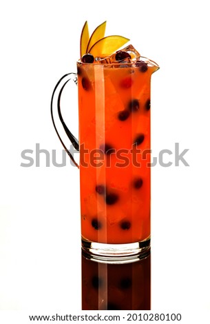 lemonade orange or peach with juice, cranberries, garnished with mango or peach or apple slices with ice cubes in a glass decanter or jug in a European style on a white background