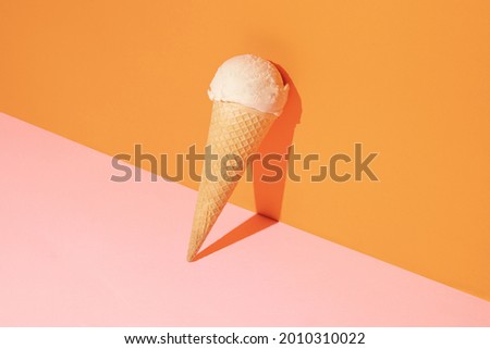 Creative compostition made with ice cream vanilla scoop and cone against pastel pink and orange background. Retro aesthetic style. Summer life style idea.