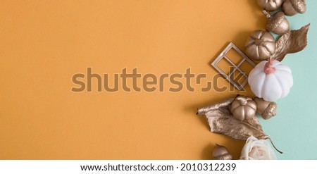 Abstract autumn background with golden pumpkins, leaves, acorns on colored paper backdrops with copy space in banner format